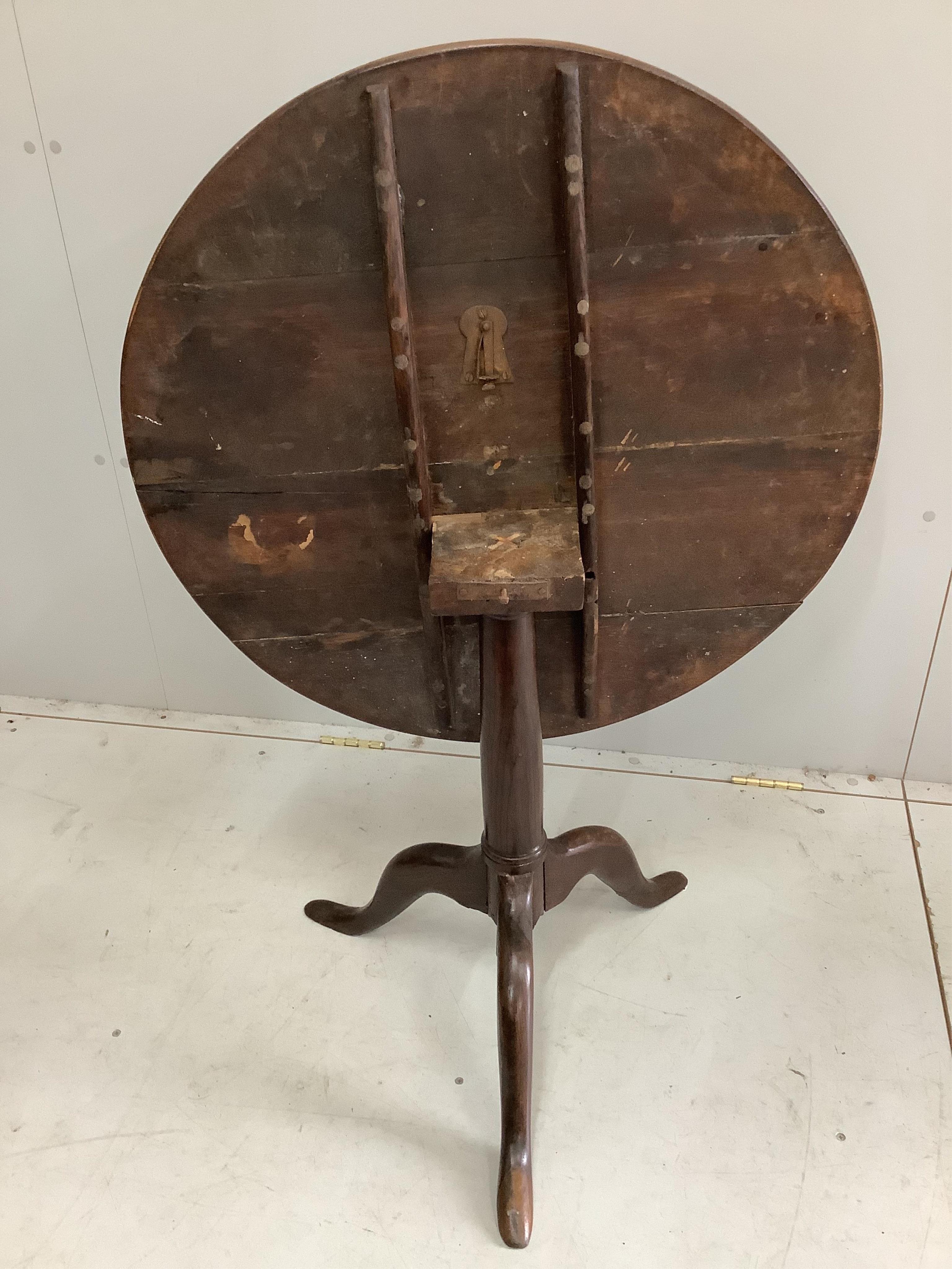 A George III circular oak tilt top tripod table, diameter 76cm. Condition - restorations